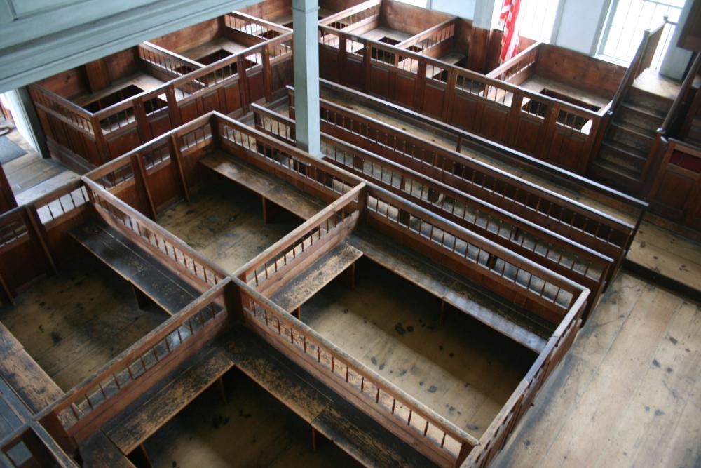 Wooden box pews with pews arranged into pods like restaurant booths