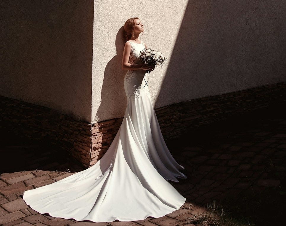woman standing beside wall holding flowers