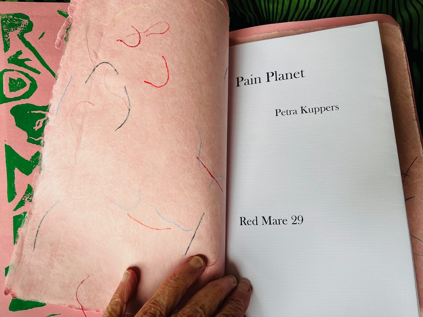 Image Description: the inside of the chapbook, with handmade papers, with the words “Pain Planet”/Petra Kuppers/Red Mare 29. Image Description: the inside of the chapbook, with handmade papers, with the words “Pain Planet”/Petra Kuppers/Red Mare 29.