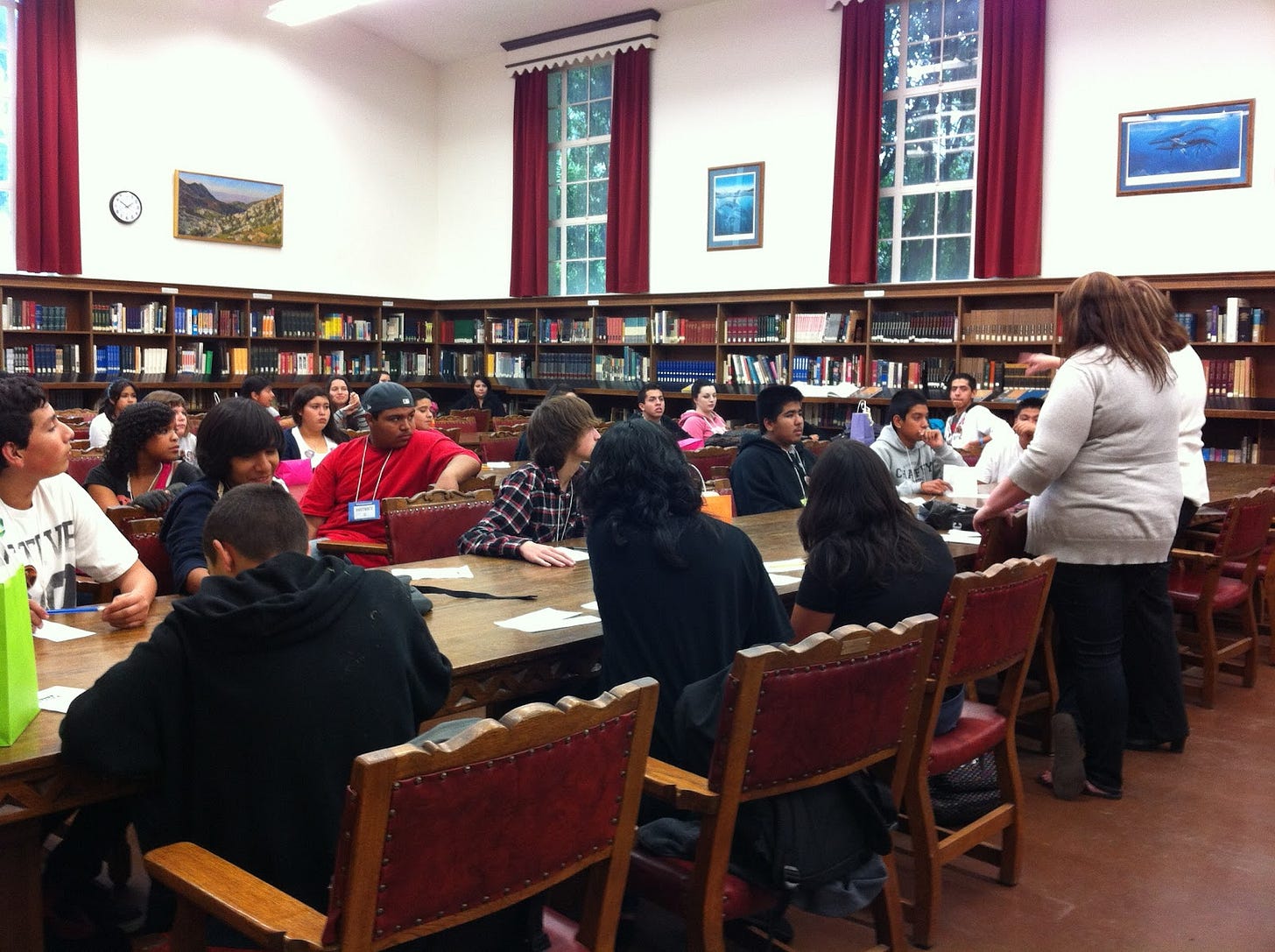 School library full of hgh school students seated at long tables.