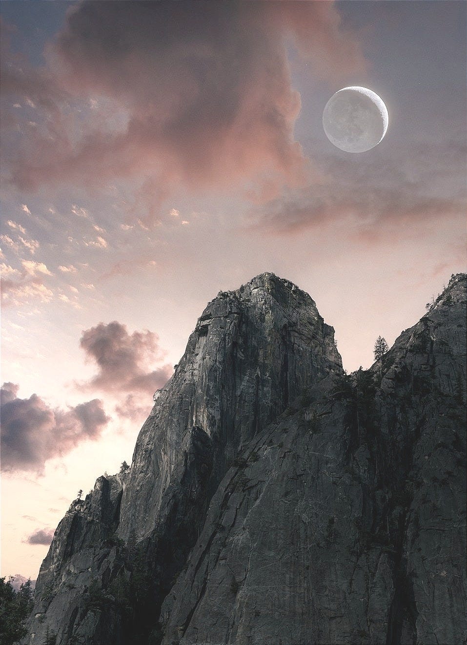 the moon is setting over a rocky mountain