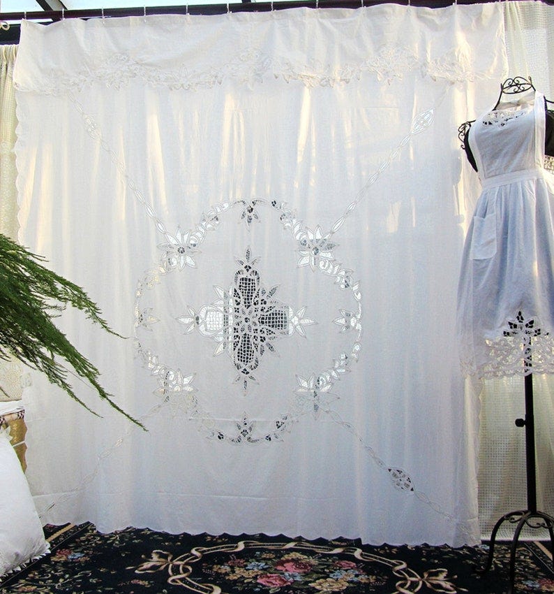 May include: White sheer curtain with a large embroidered design in the center. The design is a circle with a cross in the center. The curtain has a scalloped bottom edge.