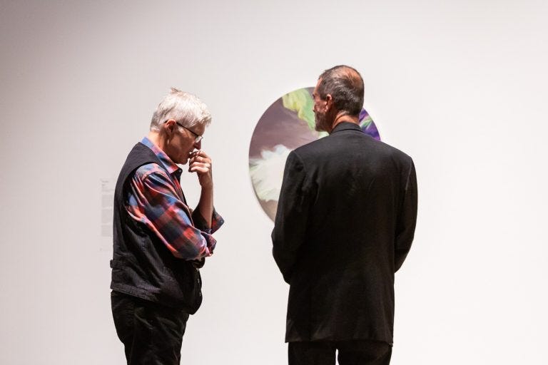Two people having a conversation in a largely white room