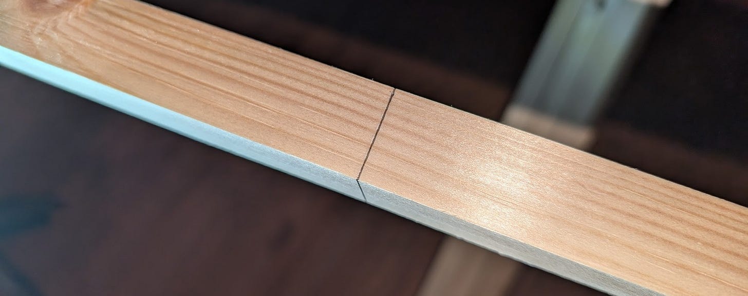 long piece of wood with a perpendicular pencil mark across the center