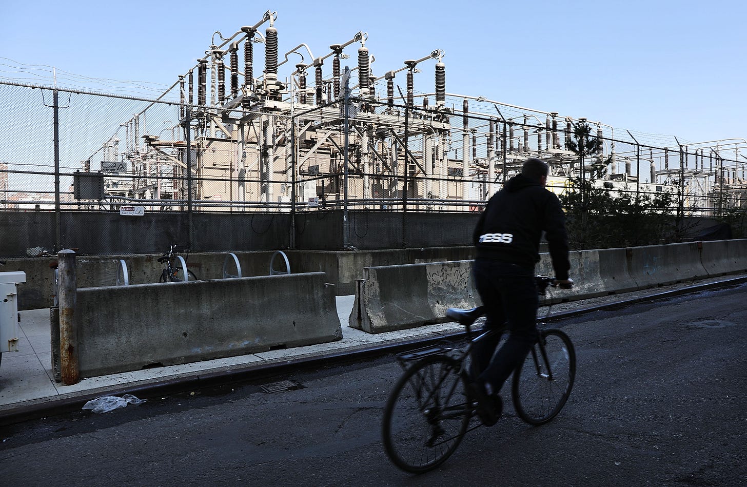 A man on a bike rides past a power plant in Brooklyn, N.Y. A man on a bike rides past a power plant in Brooklyn, N.Y.