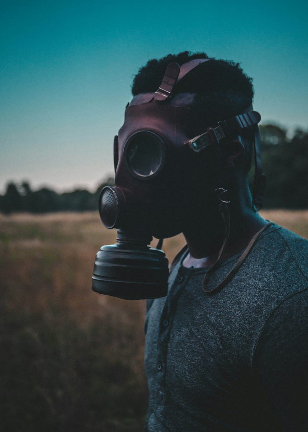 man wearing brown gas mask standing on brown field man wearing brown gas mask standing on brown field