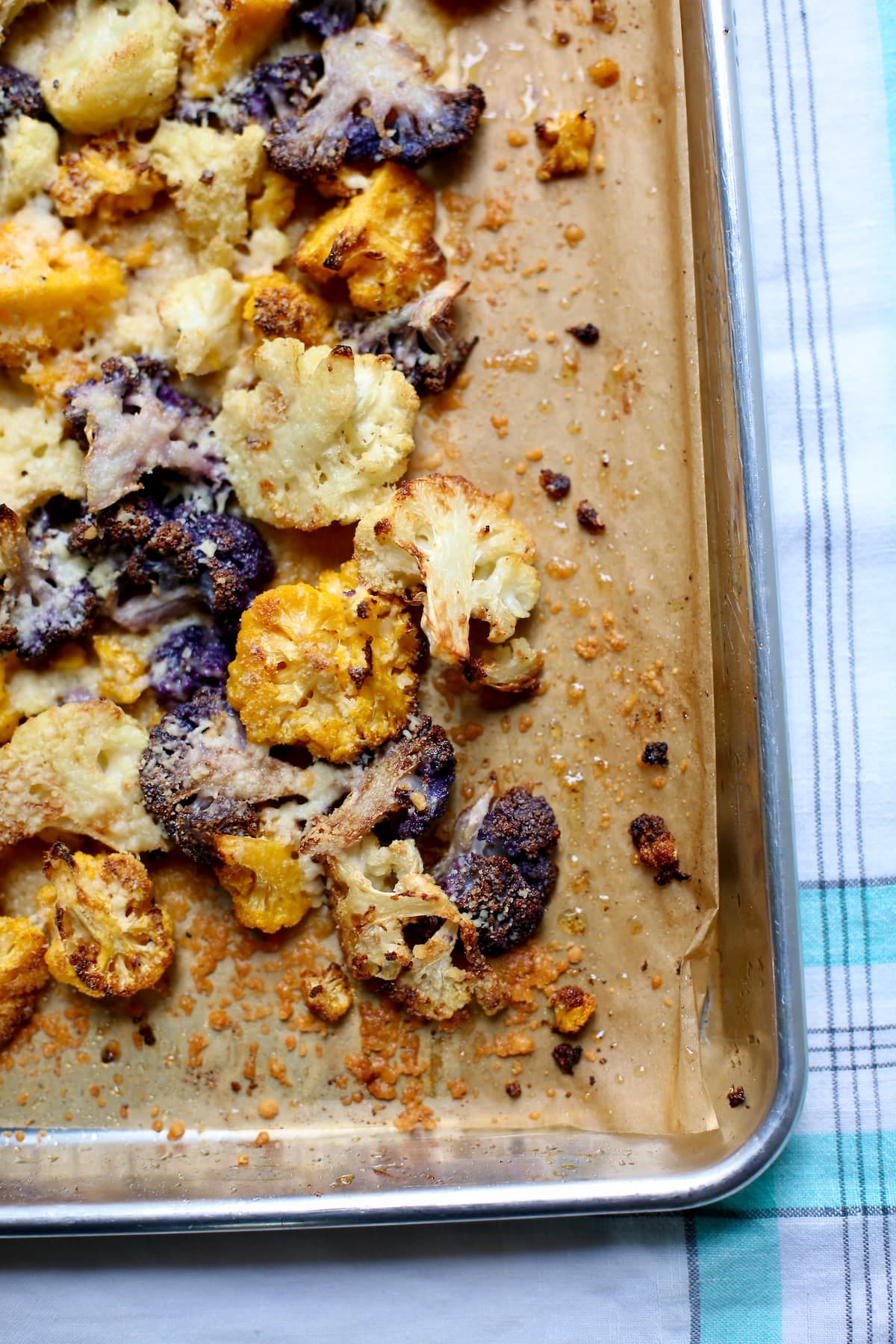 a baking sheet with parchment paper of roasted multi-colored cauliflower.