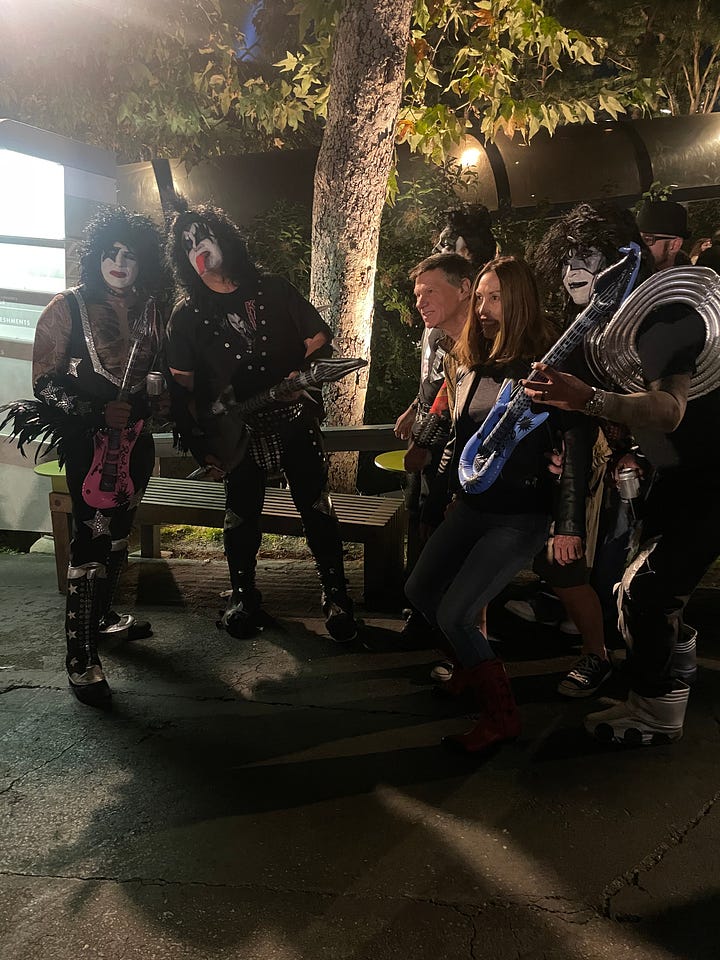 image on the left: KISS fan wearing KISS shirt in front of sign that says Captain's lounge. Middle image is mother and child wearing KISS make-up on the bus. Right image is KISS fans dressed up in make-up taking photos with non-make-up fans
