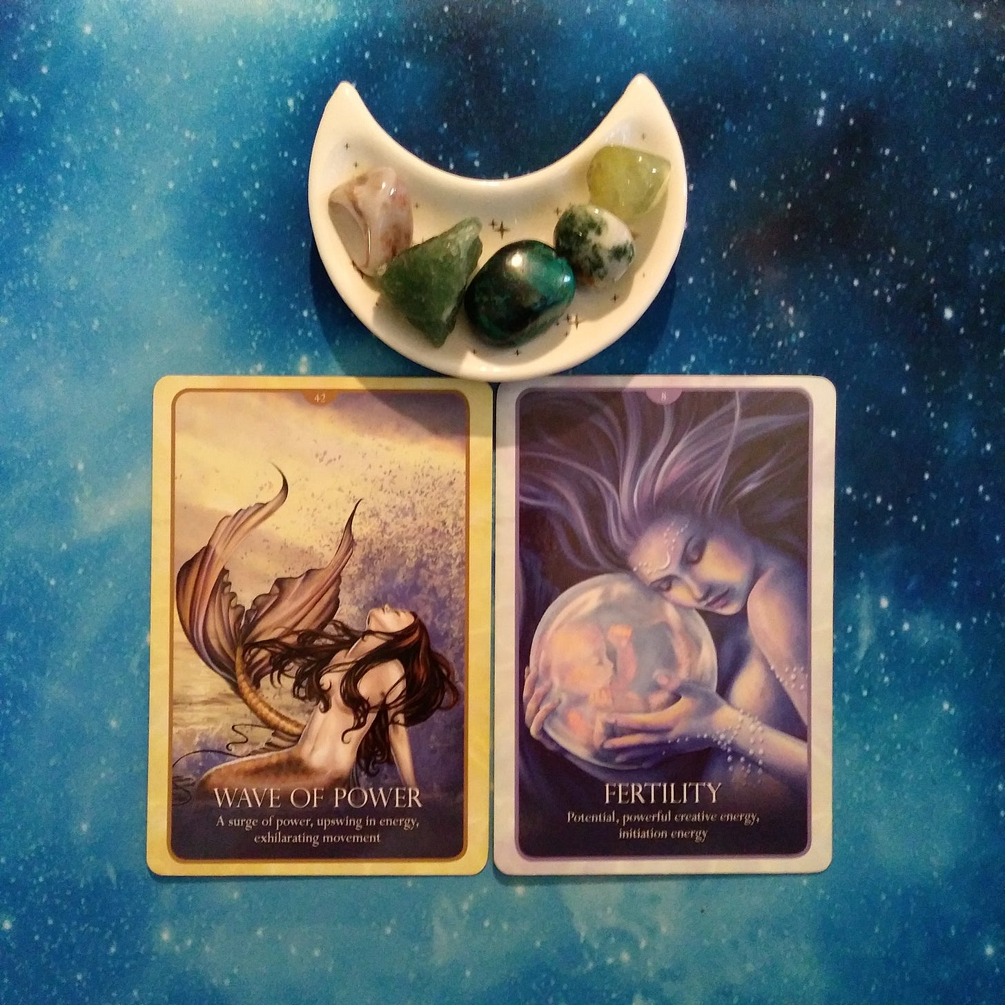 2 Oracle of the Mermaids cards and crystals on a starry blue background