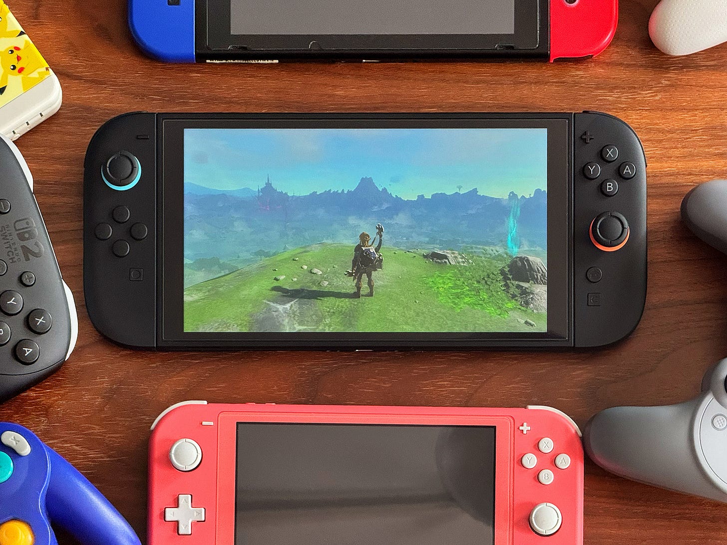 Close-up photograph of the Switch 2 surrounded by other Nintendo handheld consoles and controllers