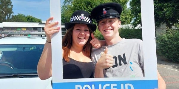 Two members of the public wearing police hats at a previous open day