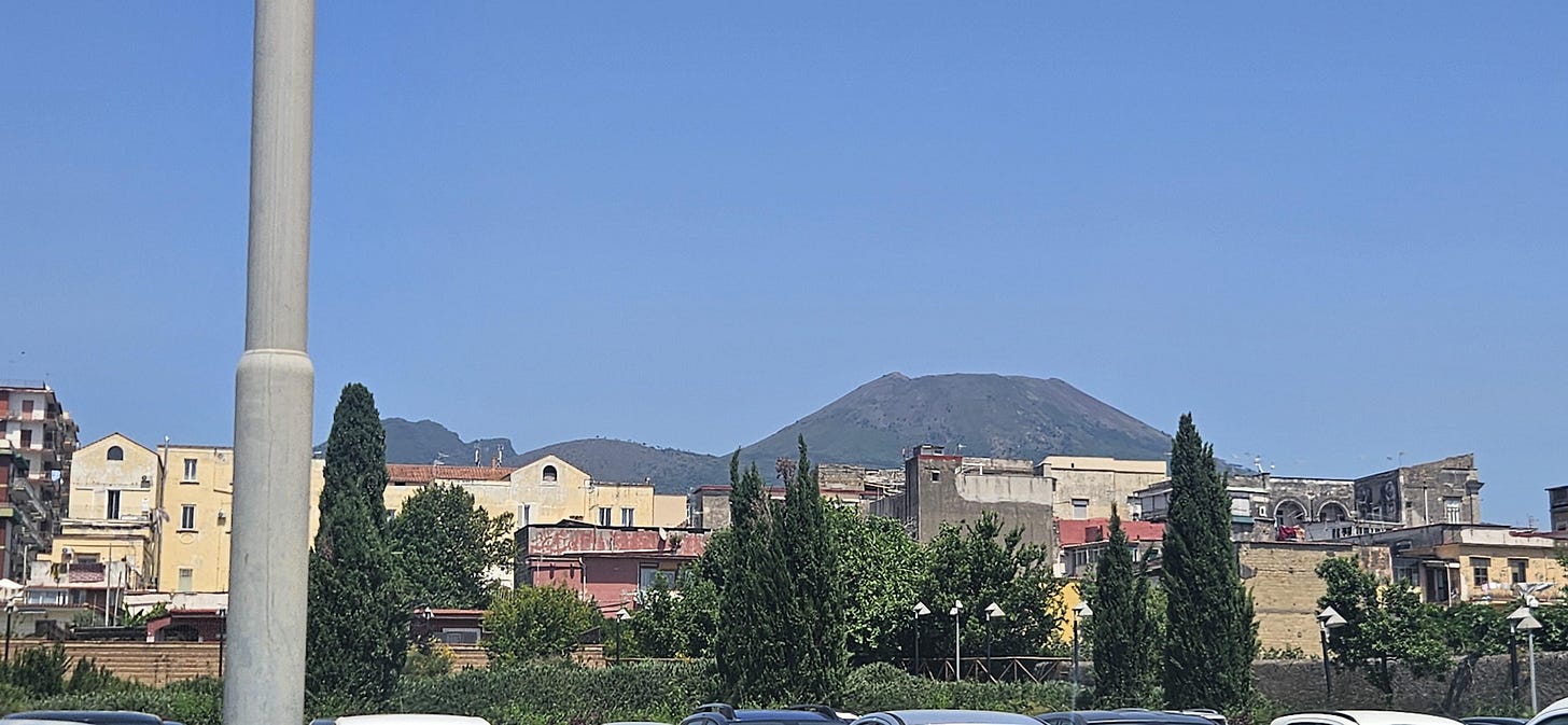 Mount Vesuvius looks more like rolling hills from a part closer to the ruins of Herculaneum than the prominent peak seen in Pompeii. Mount Vesuvius looks more like rolling hills from a part closer to the ruins of Herculaneum than the prominent peak seen in Pompeii.