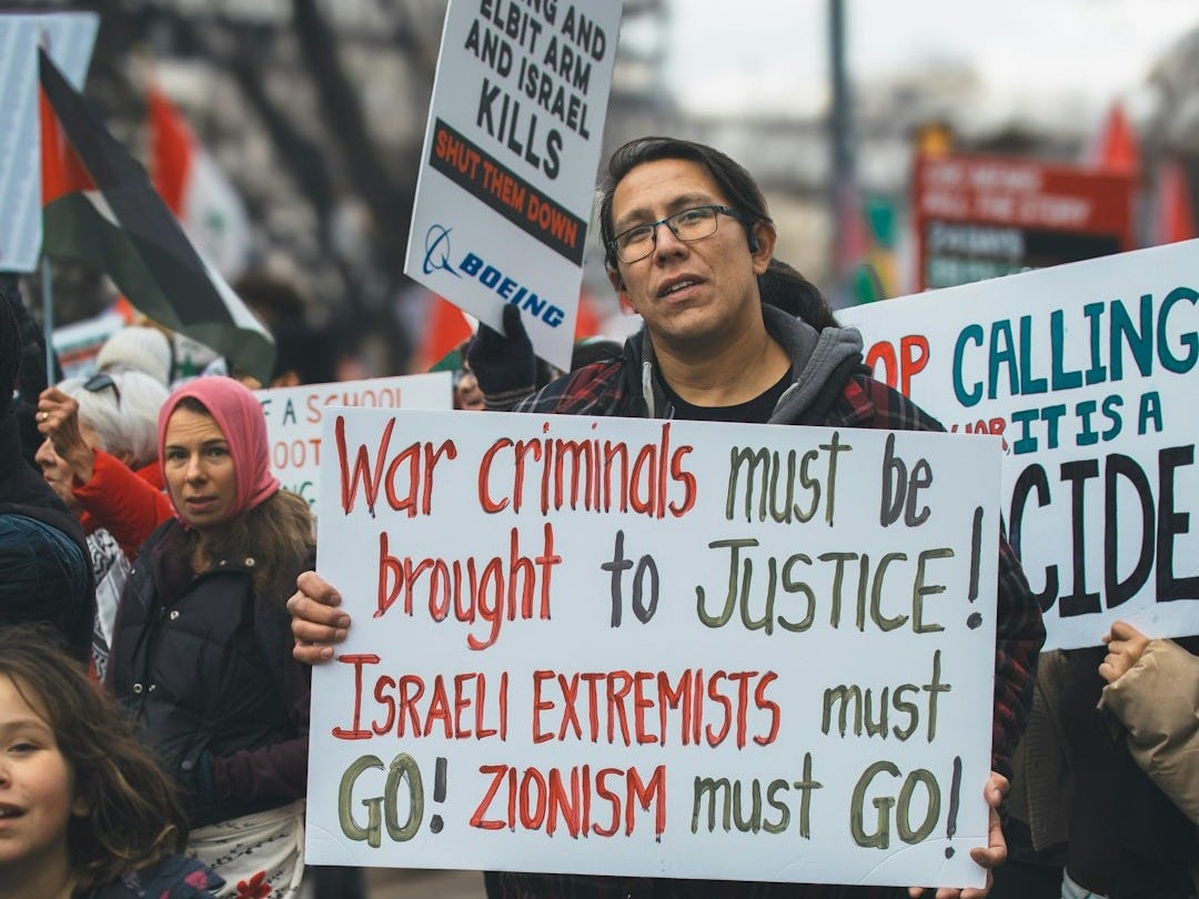 a man holding a sign in front of a crowd of people a man holding a sign in front of a crowd of people