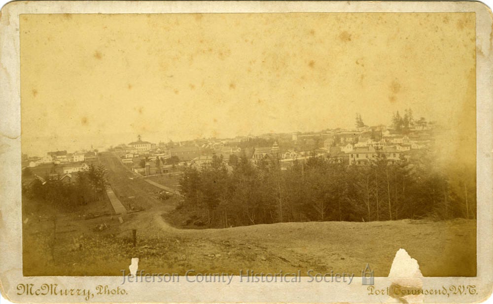 A historic wide view of Uptown Port Townsend from Morgan Hill during the late 19th-century development period shows the Albert C. Adams House under construction.