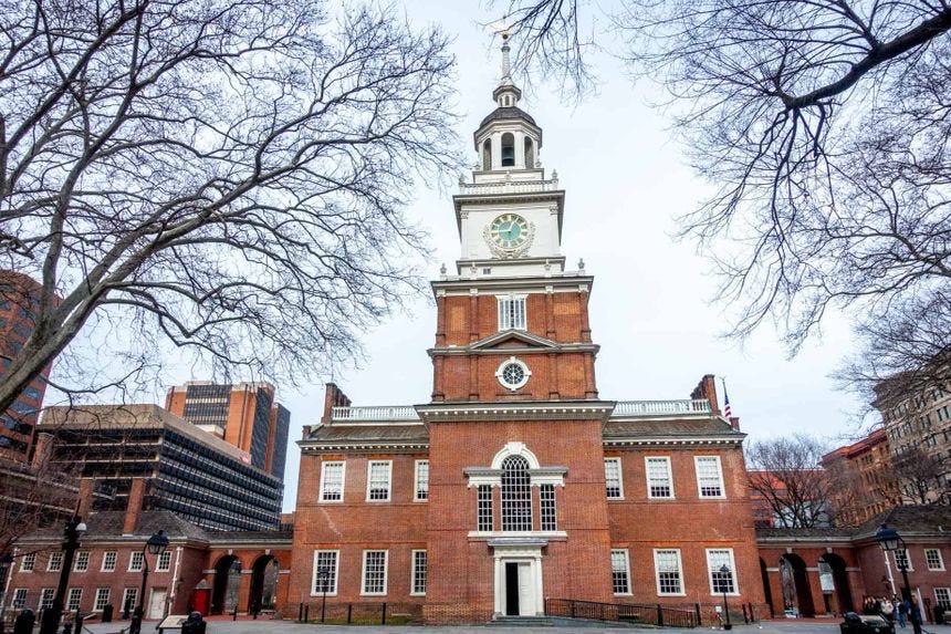 Exterior of a complex of brick buildings, one of which has a large clock tower.