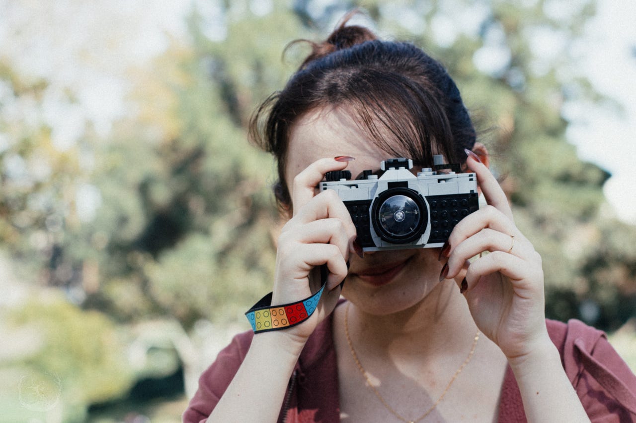 A photo of a student taking a pretend photo using a toy Lego camera.