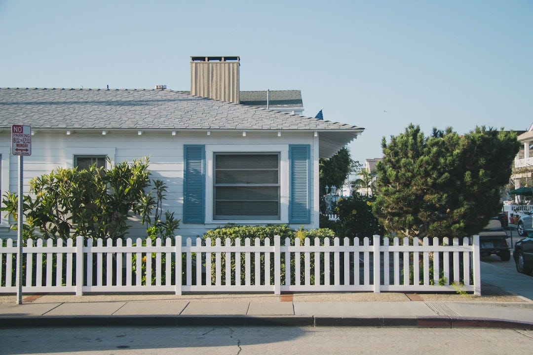 white and blue house beside fence white and blue house beside fence