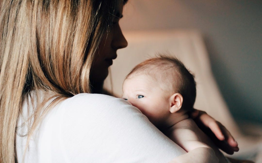 woman in white shirt carrying baby