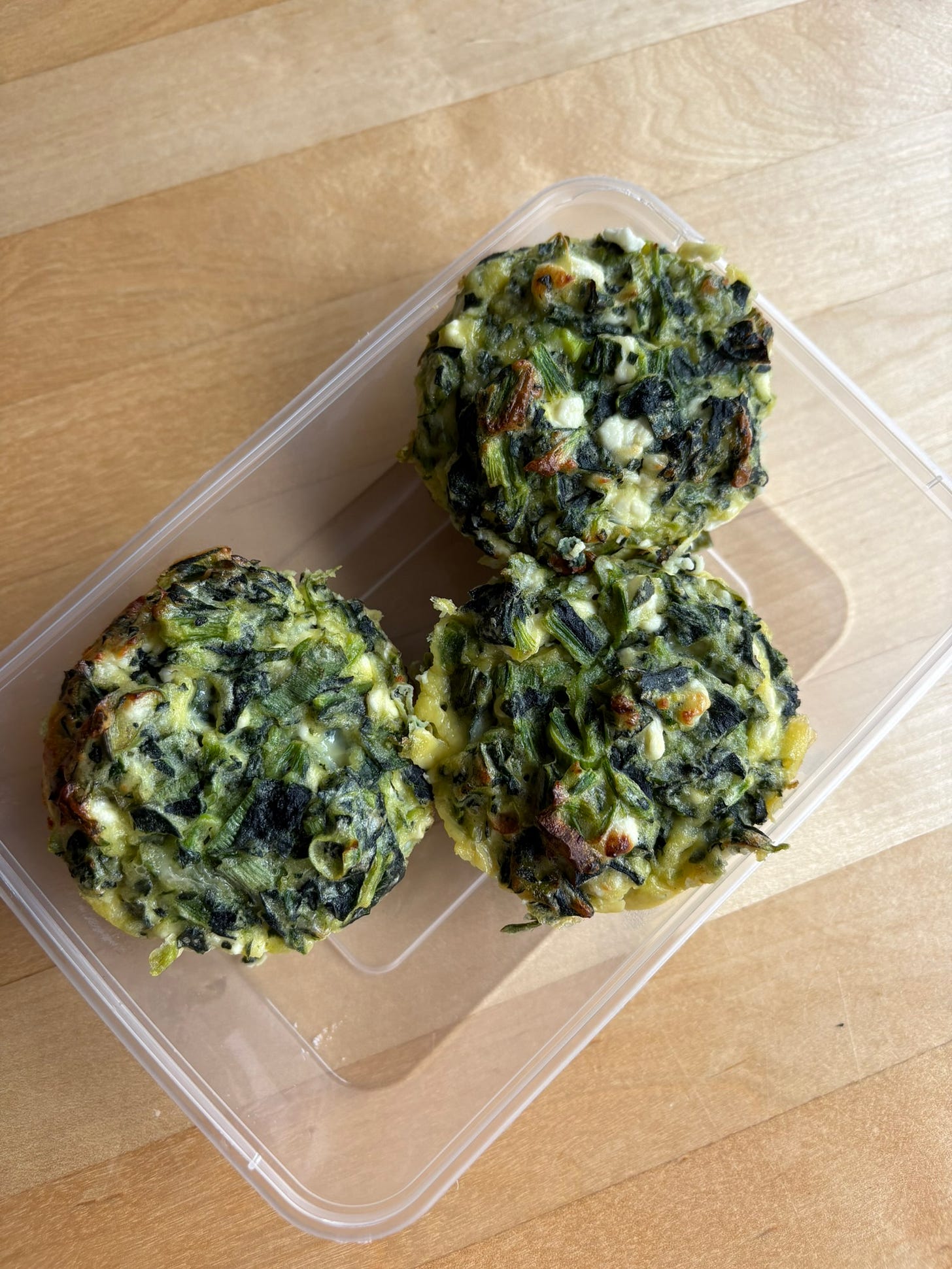 Three spinach muffins in a takeaway container Three spinach muffins in a takeaway container