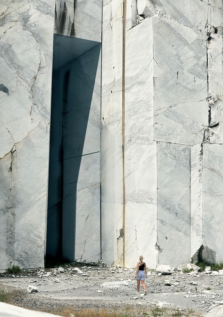 This may contain: a woman is standing in front of a large rock structure with a door on it's side