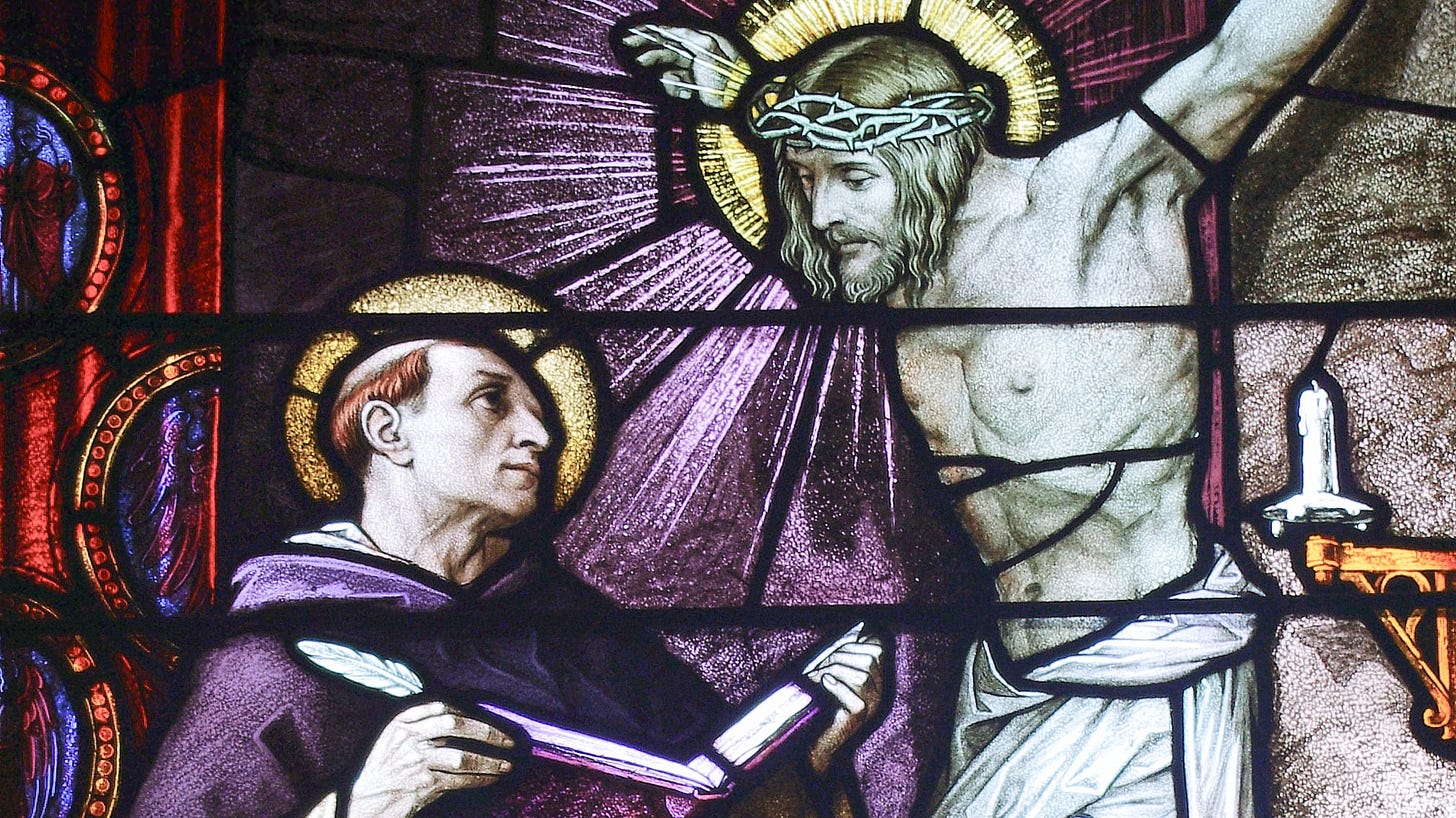 St. Thomas, holding a book and standing below a crucifix.