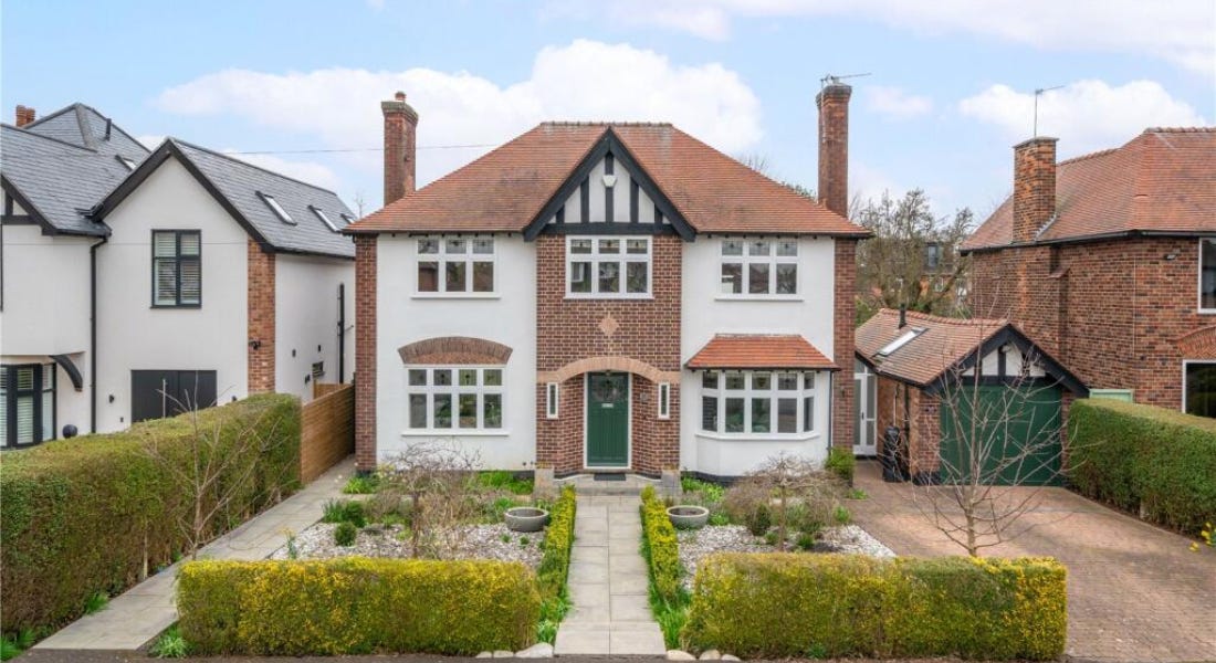 A large house with a white and brick exterior, a symmetrical front garden with a path, and two houses either side A large house with a white and brick exterior, a symmetrical front garden with a path, and two houses either side