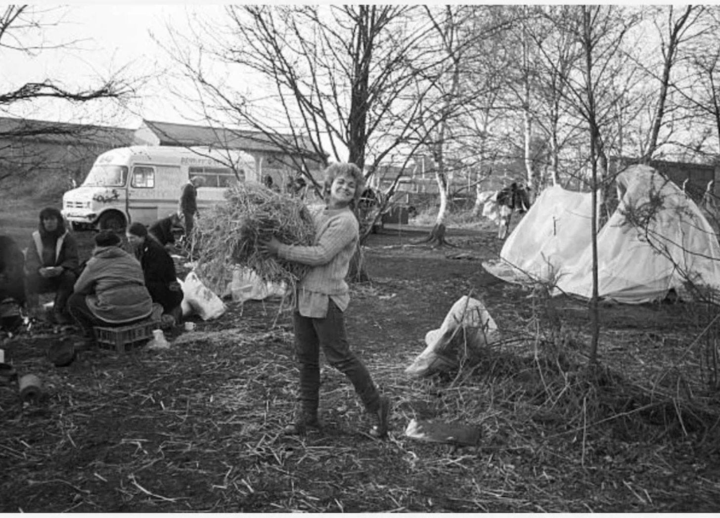 A woman gathers sticks at a camp A woman gathers sticks at a camp