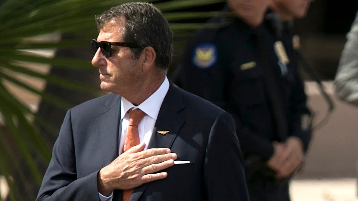 Douglas McCain has his hand on his heart at his father's funeral
