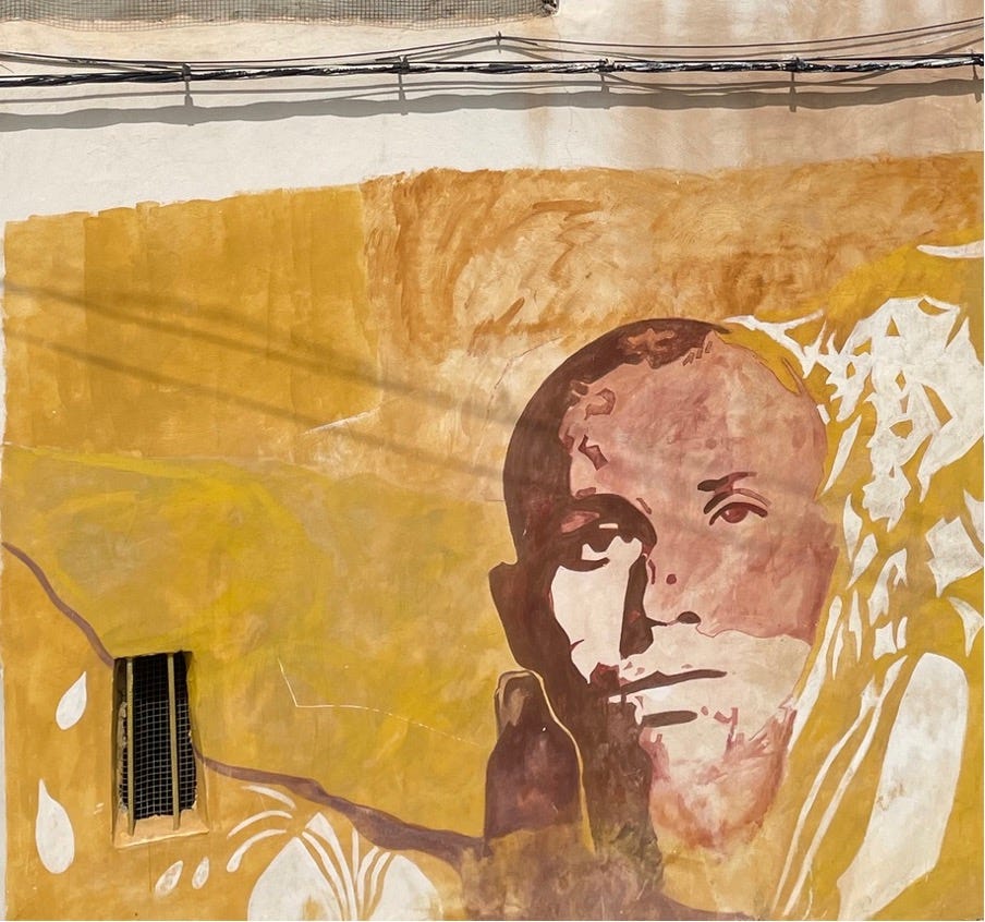 A mural of a face against an earthly yellow backdrop.
