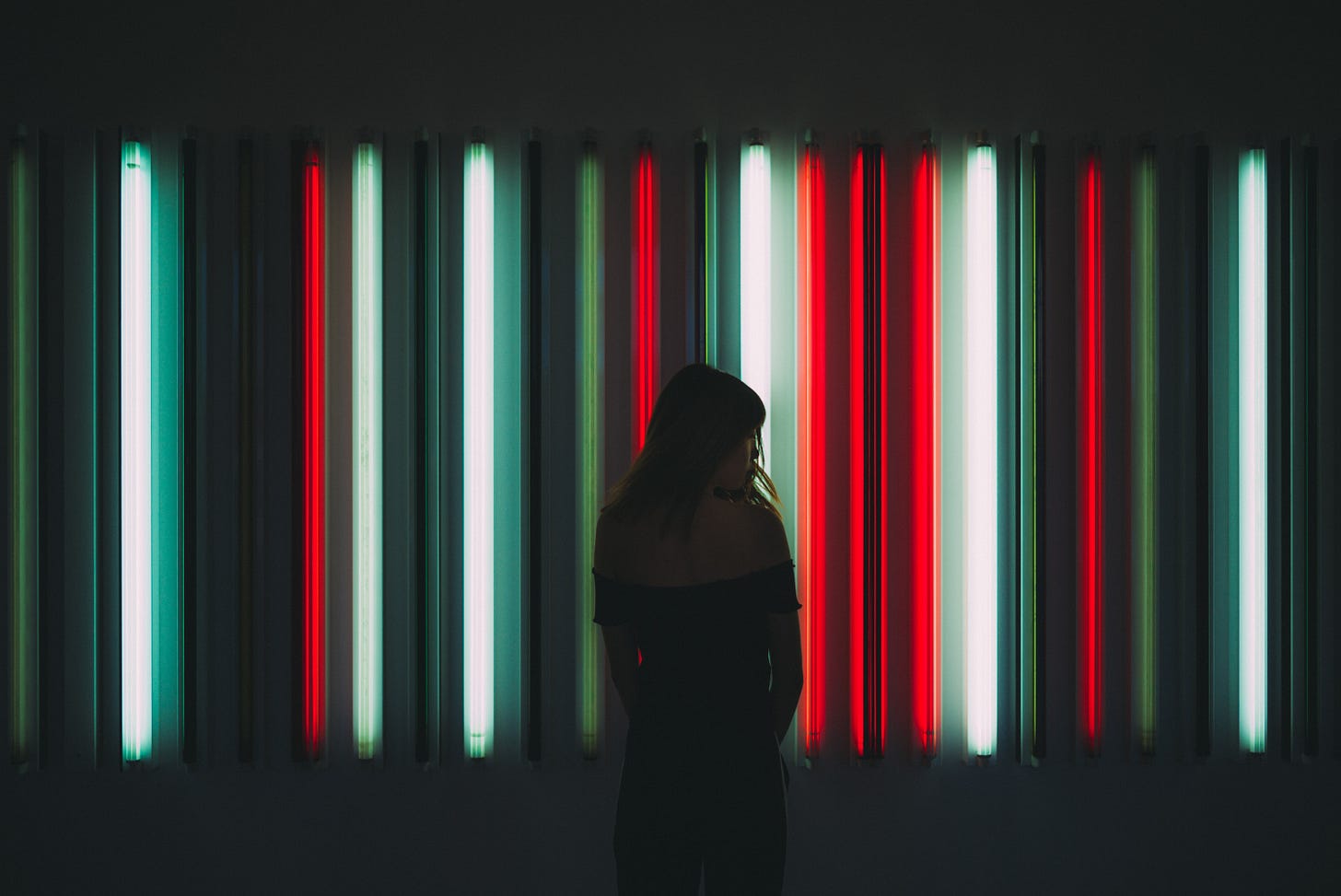 woman in black in front of neon strip lights.