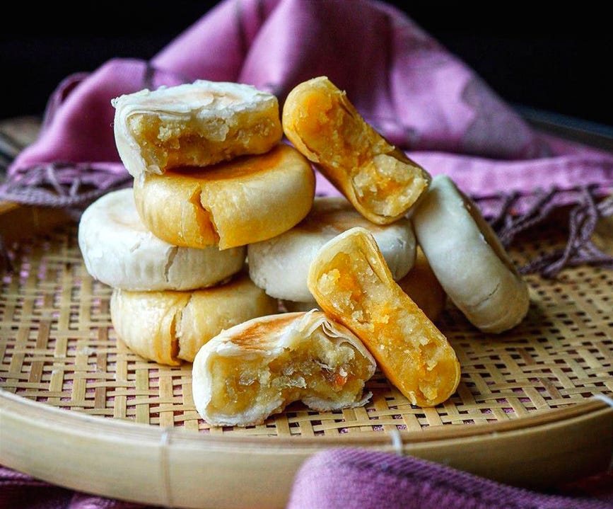 A stack of pia cakes, which are round with a thin flaky pastry crust and soft mushy filling such as mung bean or durian puree.