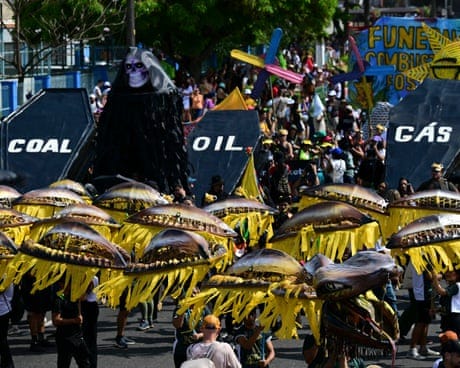 People in bright costume carry coffins labelled coal, oil and gas in a parade