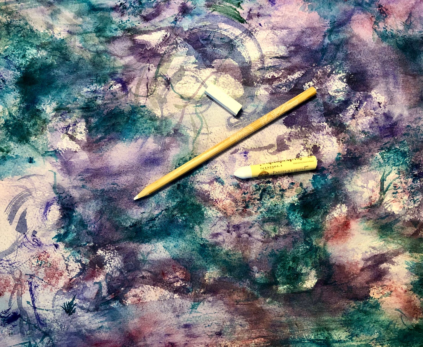 A vibrant abstract watercolour paintings with purples, pinks, and turquoises. On top of the paintings rests three white-coloured drawing materials: a pencil crayon, a soft pastel, and an oil pastel.