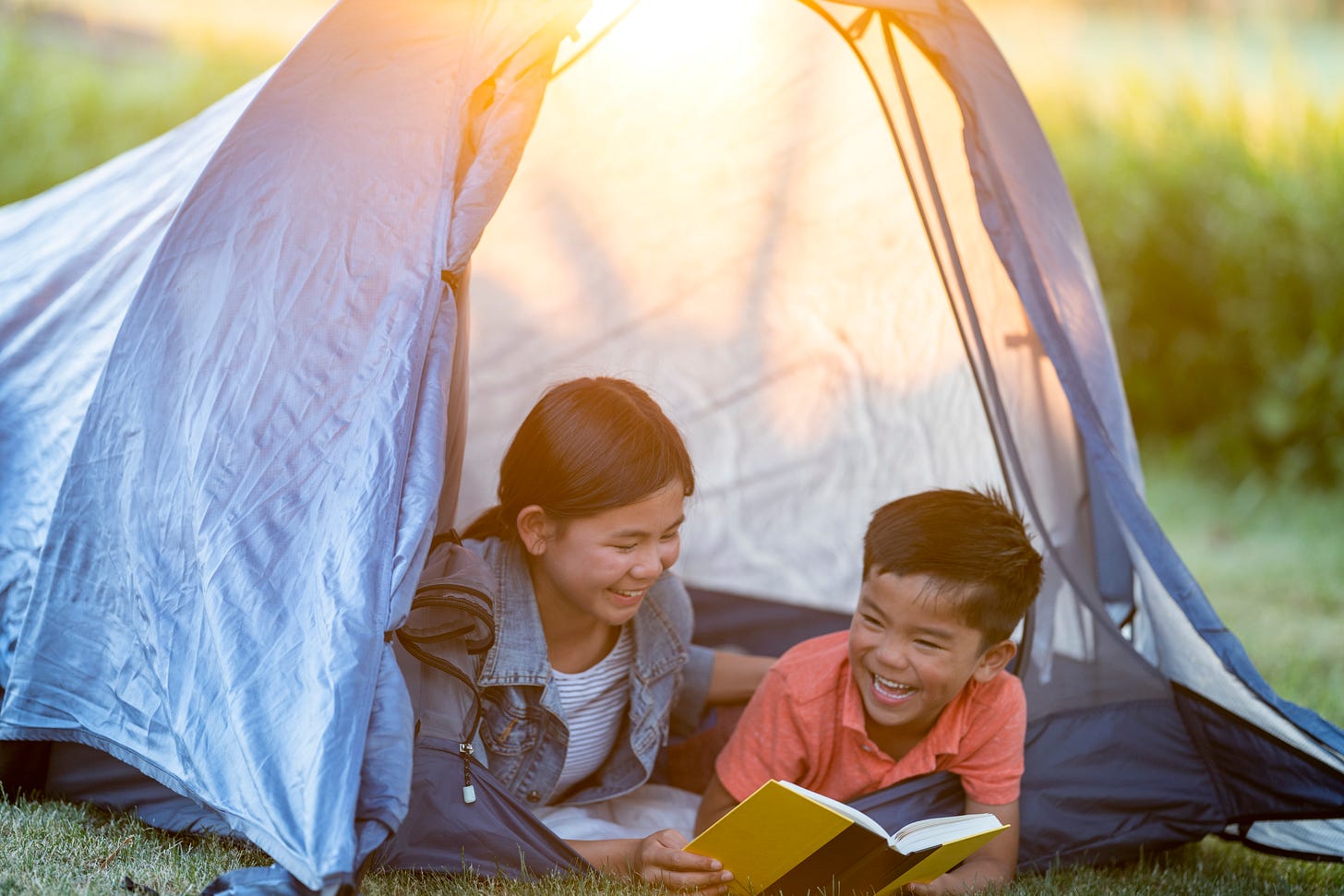 Kids reading a book in a tent. Kids reading a book in a tent.