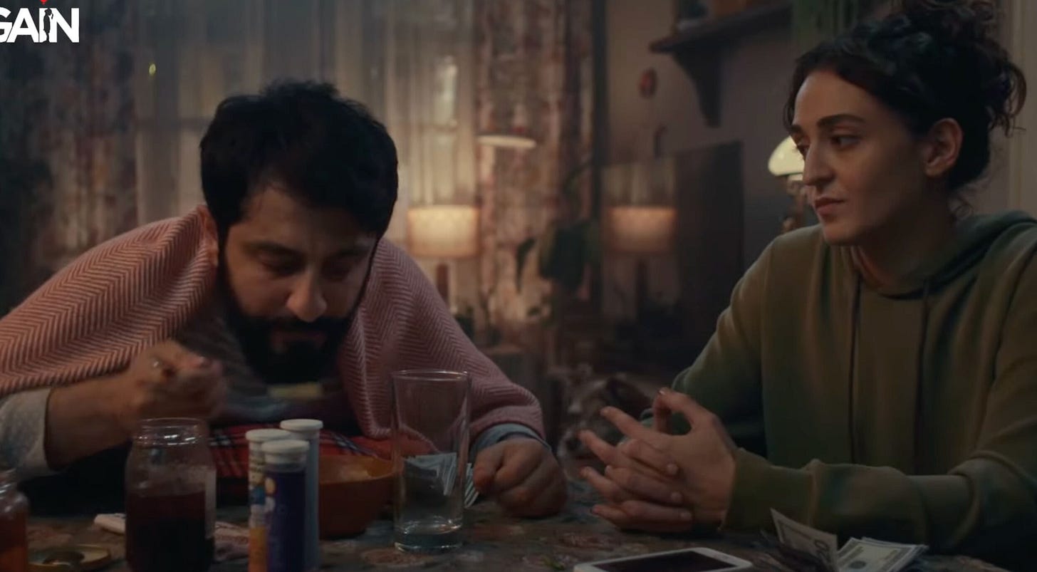 GAİN logosunun yer aldığı bir sahnede, iki karakter akşam yemeğinde bir masada oturuyor; masada içecekler, reçel kavanozu ve para dikkat çekiyor. GAİN logosunun yer aldığı bir sahnede, iki karakter akşam yemeğinde bir masada oturuyor; masada içecekler, reçel kavanozu ve para dikkat çekiyor.