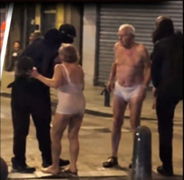 Two elderly people in underwear are standing on the street, a woman and a man, who are being approached by a man in black clothing.