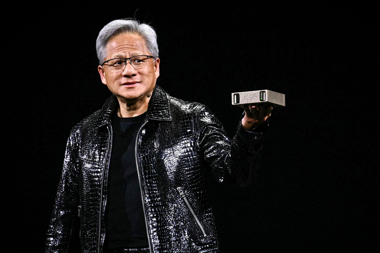 Jensen Huang holding a hardware component during an NVIDIA presentation.
