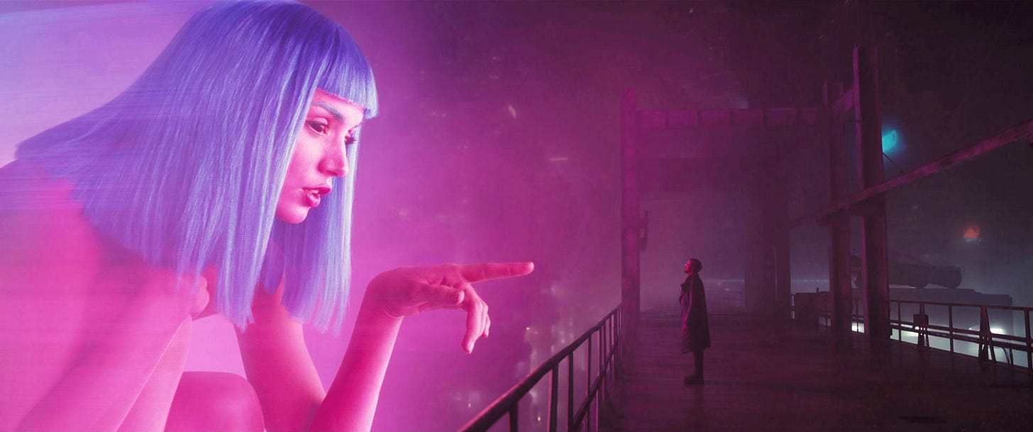 Blade Runner 2049 scene where a large-scale holographic woman with mid-length blue hair is pointing towards the main character who is standing on a bridge