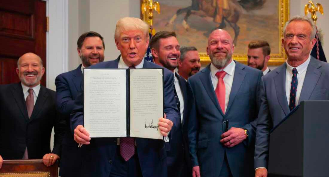 Trump displays a signed executive order, surrounded by officials and pro athletes.