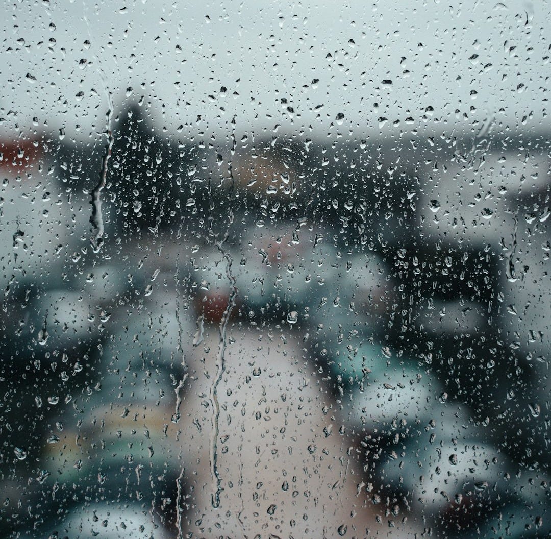 a view of a parking lot through a rain covered window a view of a parking lot through a rain covered window