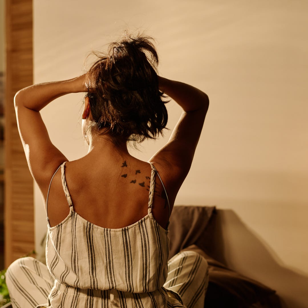 vrouw zit ontspannen met rug naar camera in warm zonlicht, moment van rust zonder afleiding