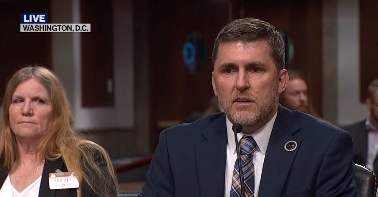 Jon Kosloski testifying before a Senate committee with Susan Gough seated beside him.