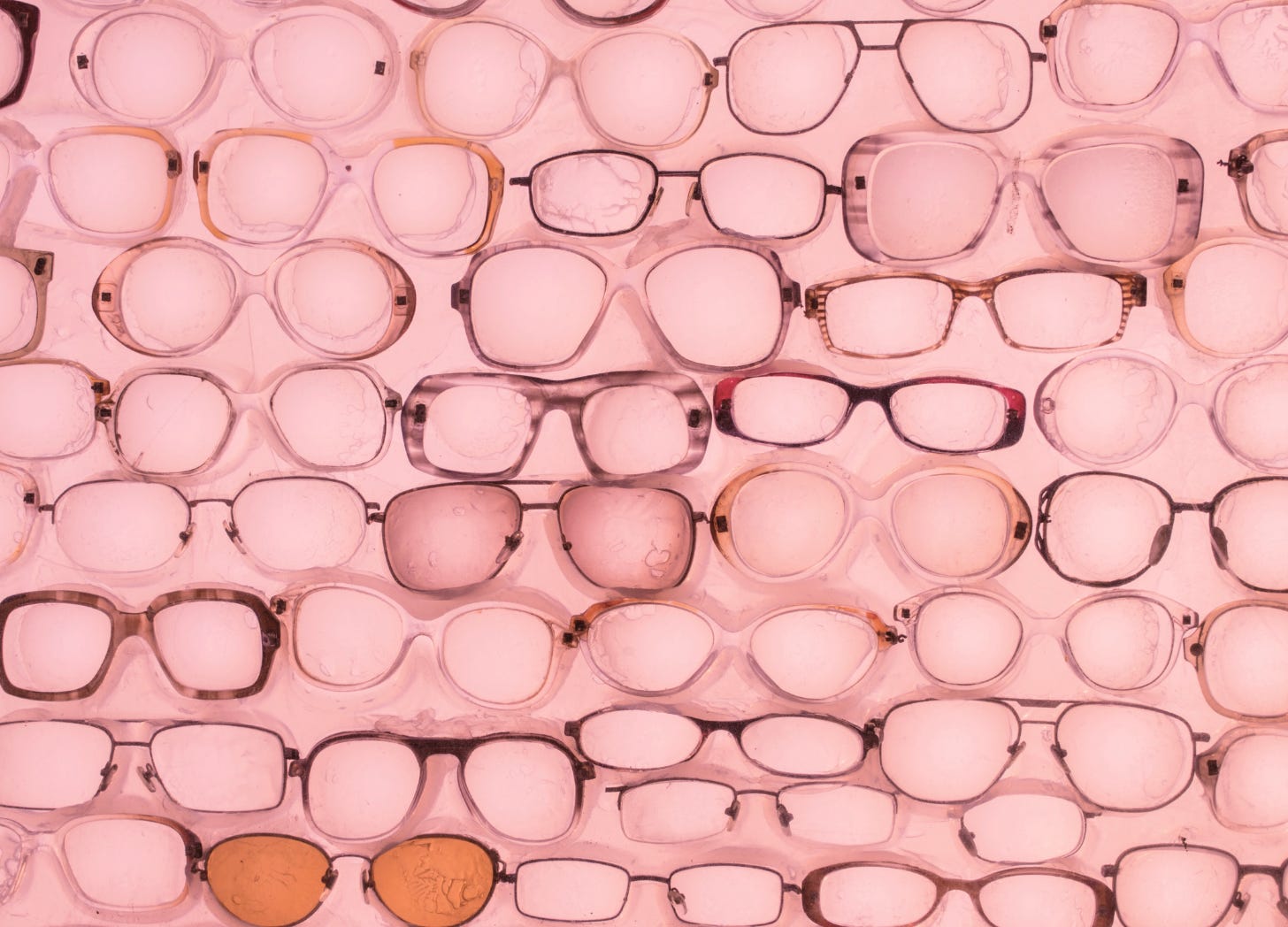 A collection of rose-colored glasses scattered across a pink background—symbolizing how comparison distorts our view of other parents’ lives, making everything look easier than it is.