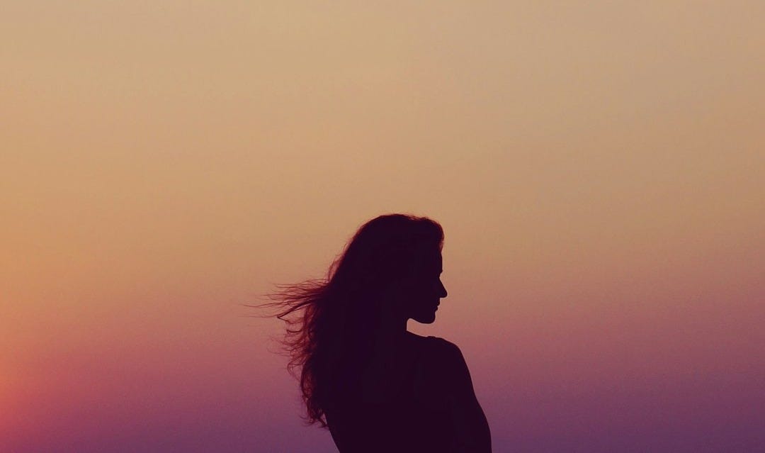 silhouette of woman under orange sky silhouette of woman under orange sky