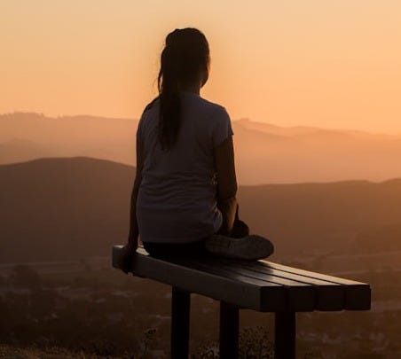 woman sitting on bench over viewing mountain