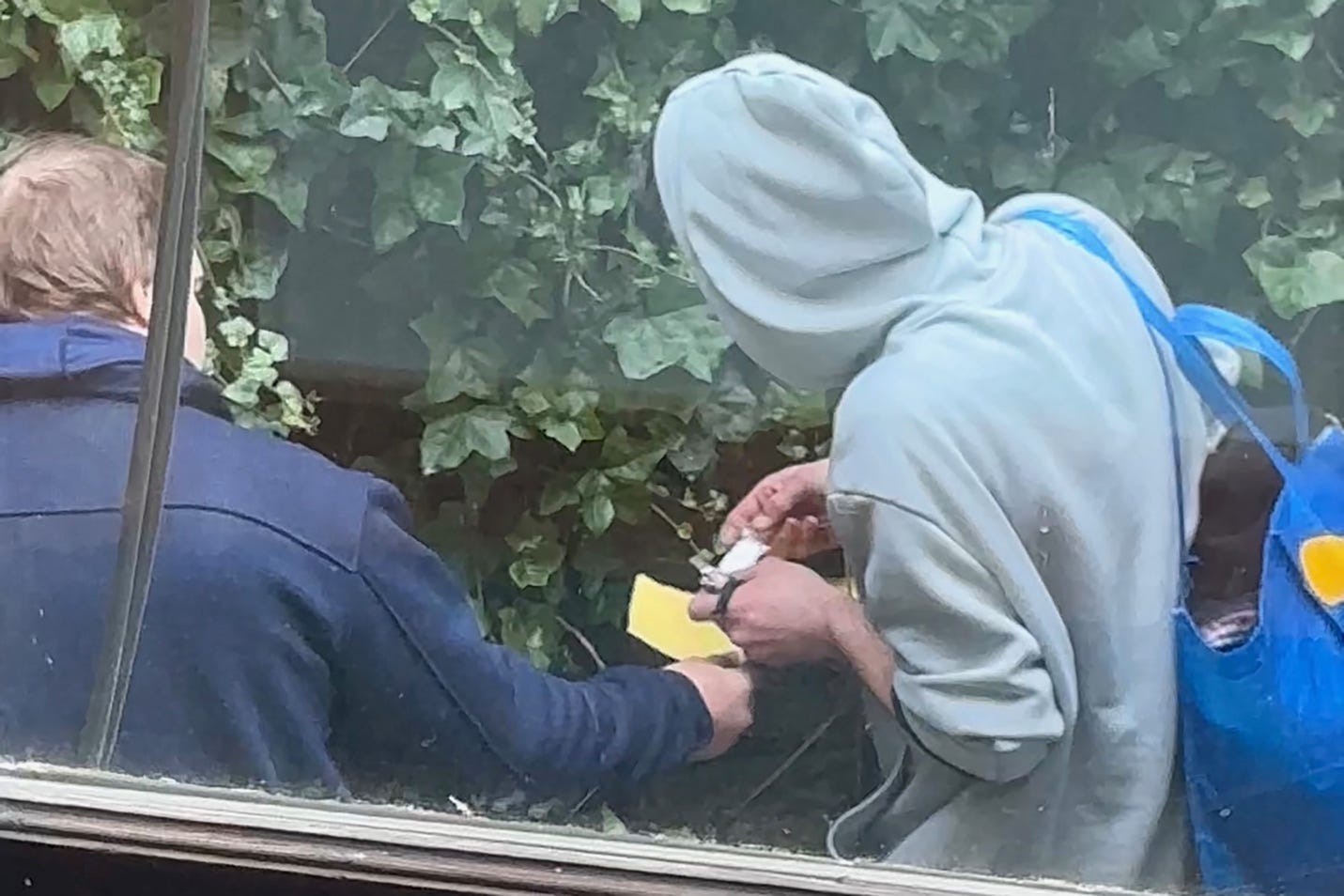 A person in a hoodie holding a piece of paper

Description automatically generated