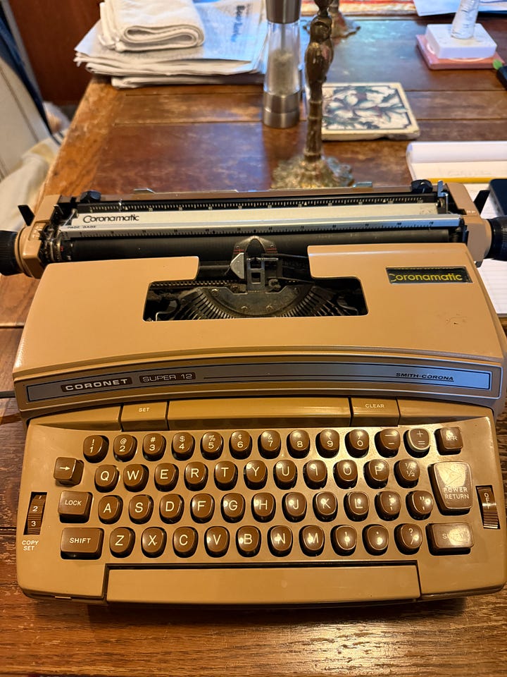 Two electric typewriters, one a black-and-cream-colored Olympia, one a caramel-colored Brother Coronet