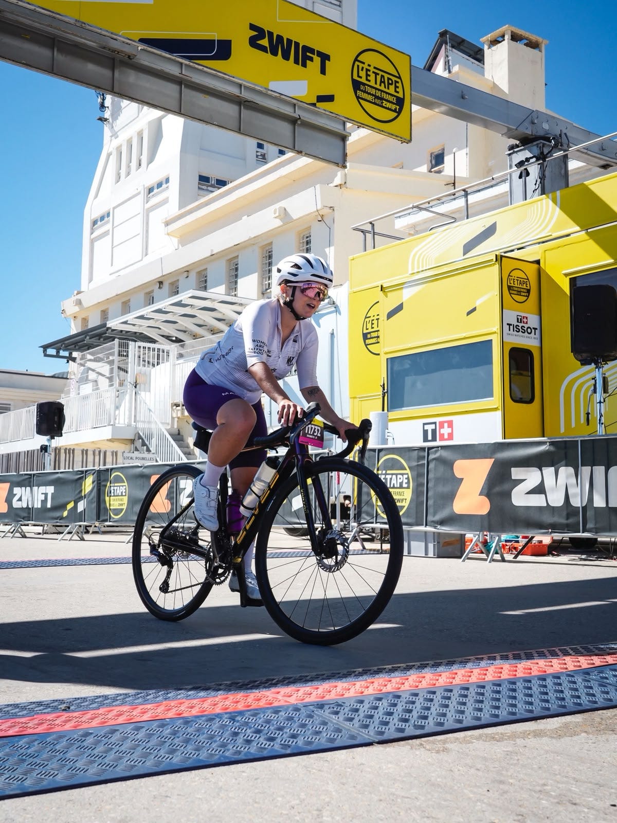Cycliste sur une route devant un camion jaune Zwift