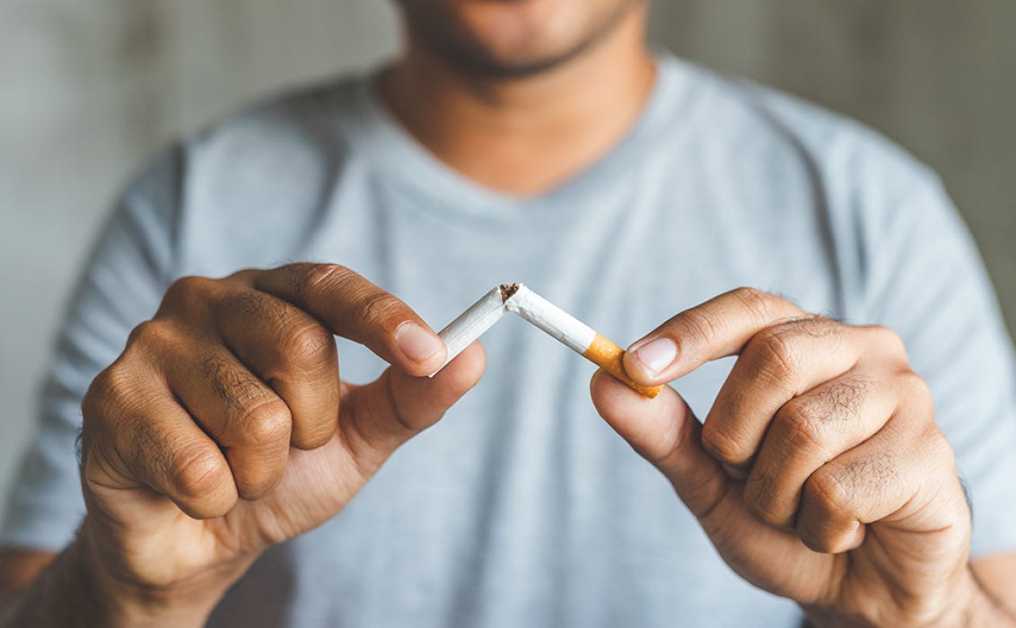 Hombre partiendo un cigarrillo en dos Hombre partiendo un cigarrillo en dos