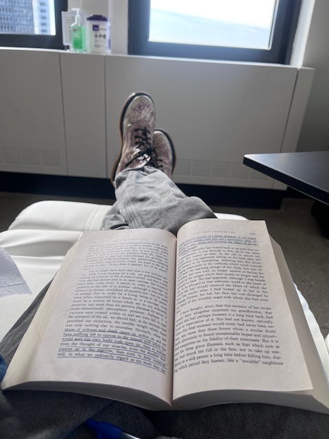 POV shot of OP's legs propped up in white recliner in front of a window showing a clear sky. There's an open book on OP's lap.